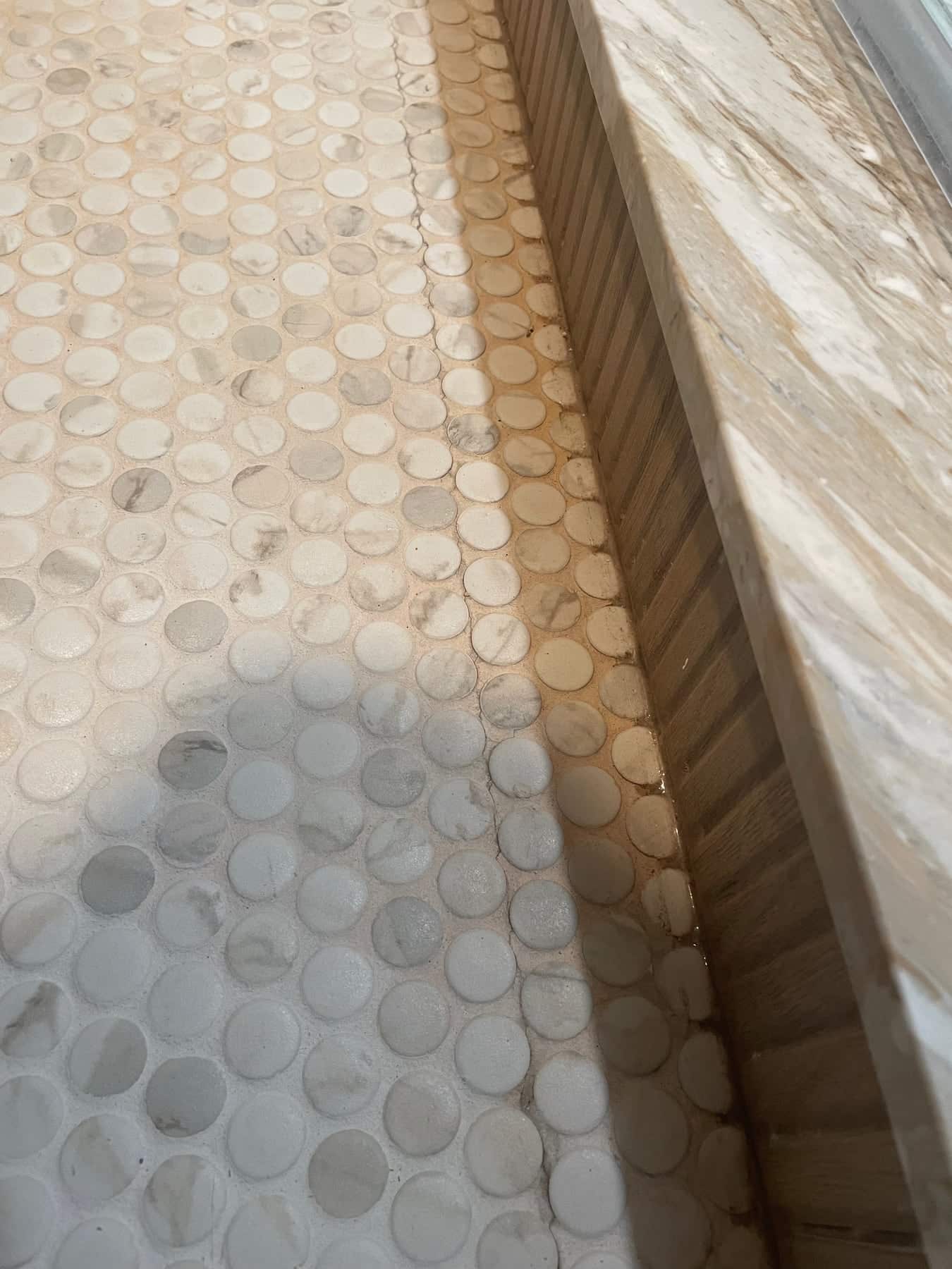 Before repair: cracked tile and grout beside the stone shower bench