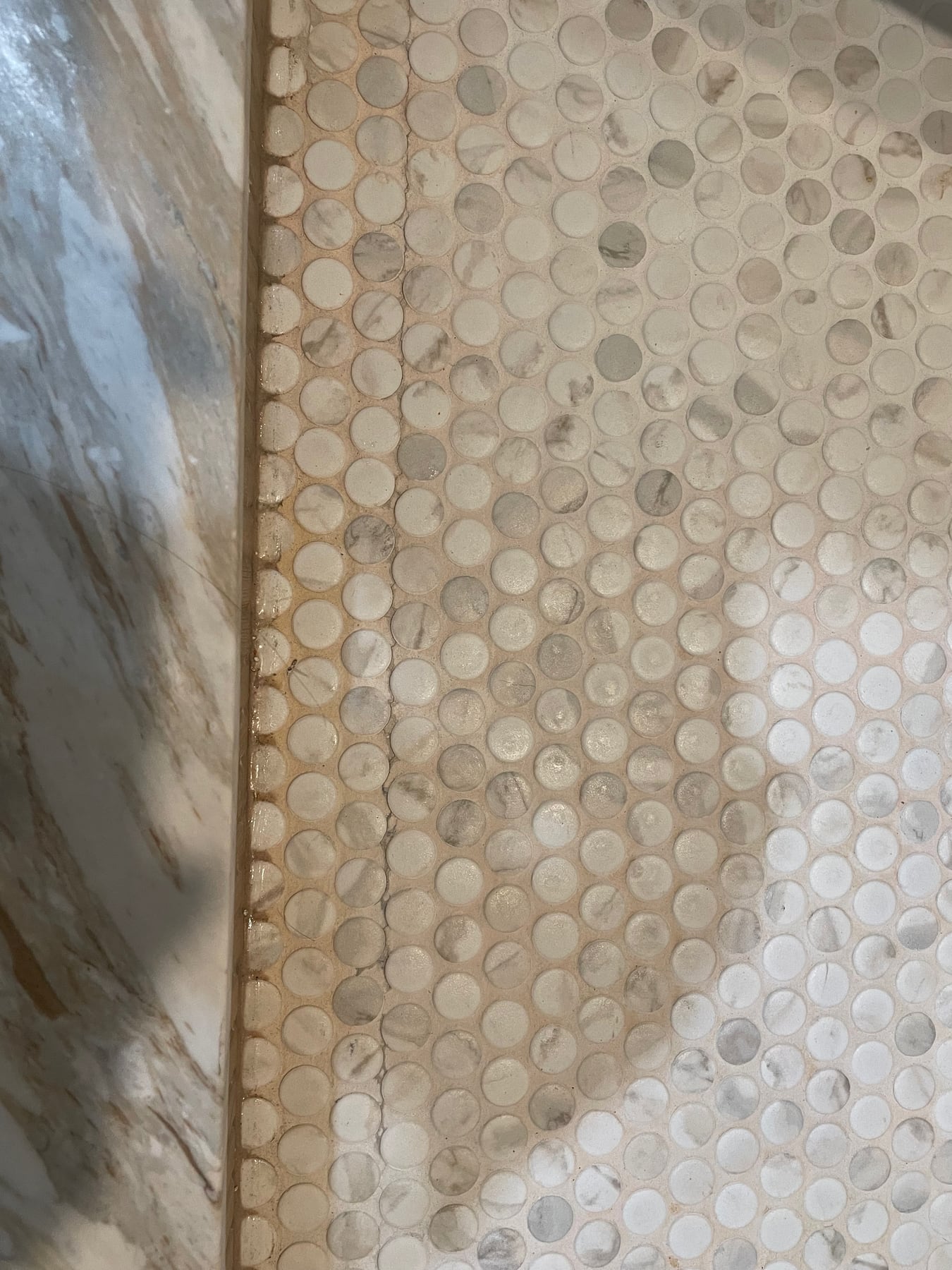 Before repair: cracking along the stone edge of a failed tile shower floor